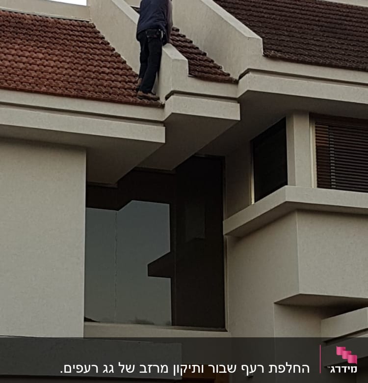 אדם מטפס על גג רעפים אדום